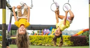 Twee meisjes hangen ondersteboven in een speeltuin